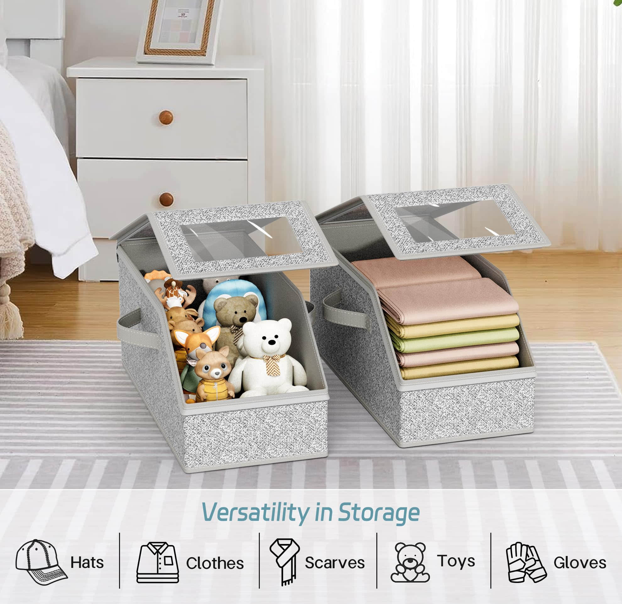 Two gray fabric stackable storage boxes with clear window lids on a bedroom floor, showing organized toys and folded clothes inside.